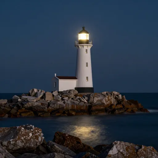 Lighthouse at night with a lit lamp and smoothed water around the rocks
