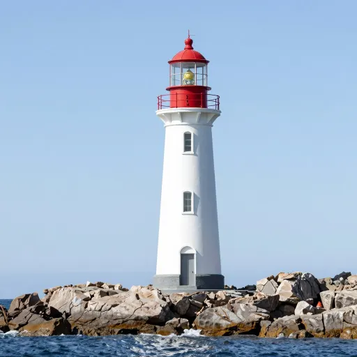 Photograph of a white lighthouse on rocks with a clear blue sky