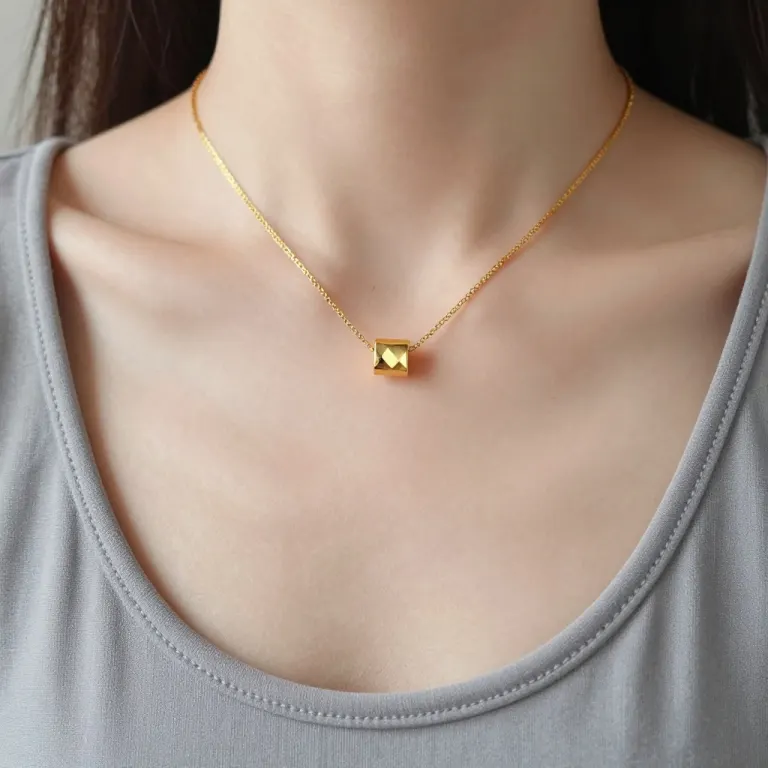 A close-up of a collarbone and a fine gold pendant necklace above a neckline