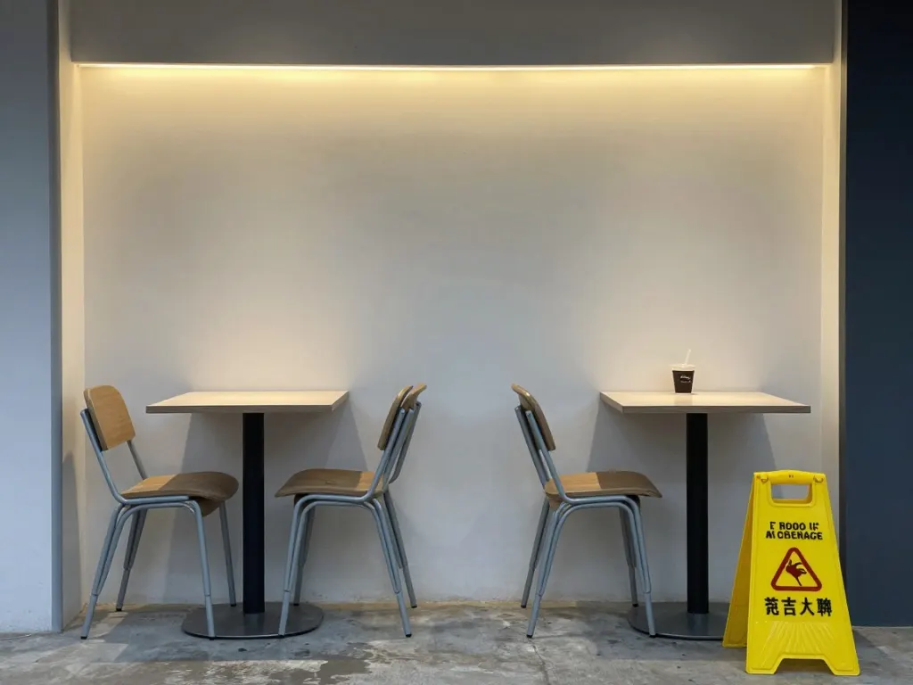 An empty cafe interior under strip lighting with a yellow wet floor sign