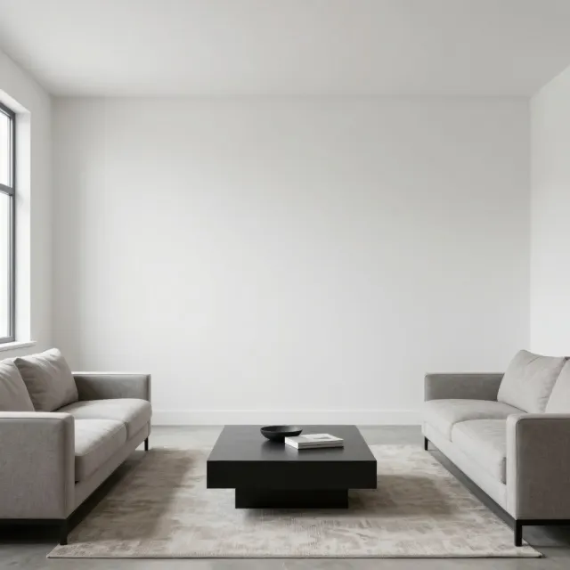 A living room with a completely blank wall and two sofas facing a table