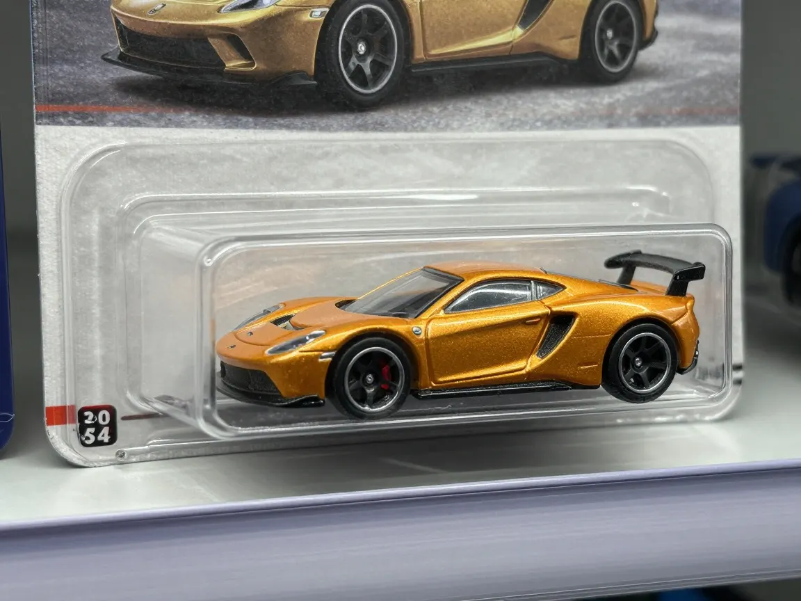 Gold die-cast sports car sealed in a blister on a printed card with a photo of the same car
