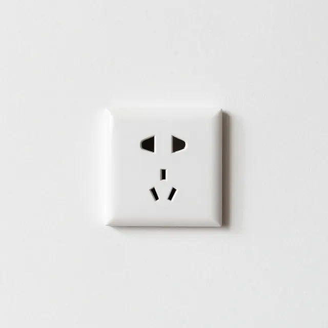 A plain white wall with a single power socket